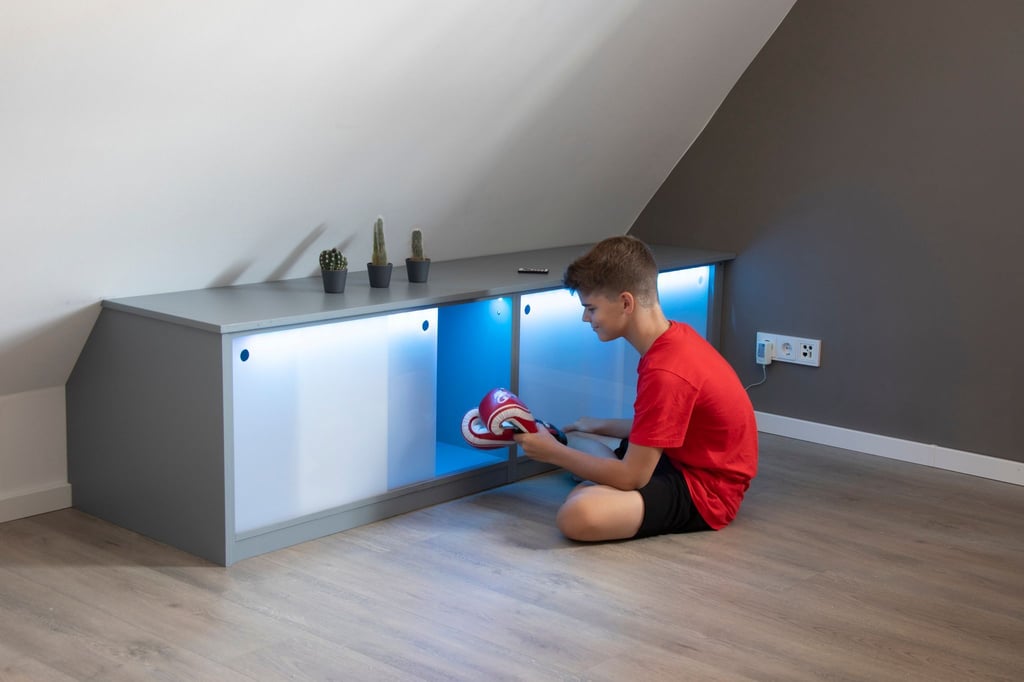 Stauraum unter der Dachschräge: Die Schiebetüren aus Acrylglas werden mit Hilfe eines LED-Bandes von innen indirekt beleuchtet.