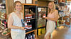 Theresa Zwicker und Aliyah Schäde vor dem Kühlschrank mit den kleinen Smoothie-Fläschchen, unten die schwarzen Standboxen. 