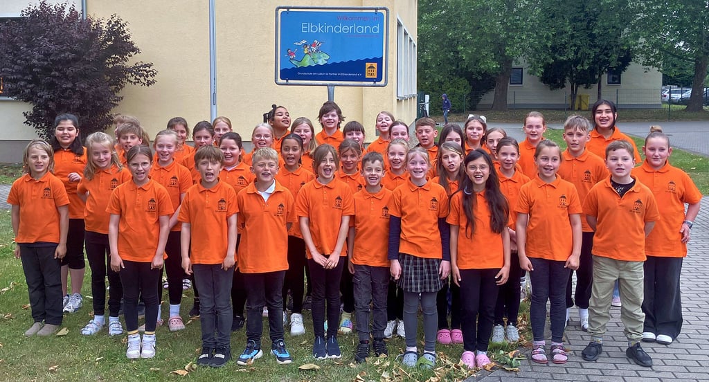 Der Chor der Grundschule am Luisium steht stolz vor dem Elbkinderland-Schild, dass 2019 vor der Schule aufgestellt wurde.