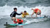 Auch Hunde können sich fürs Surfen begeistern - aber Schwimmwesten sind Pflicht.