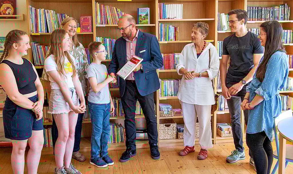 Der zwölfjährige Philipp (12) nimmt von Jan Goldacker, Vorstand der Sparkasse, das 1.000-Euro-Preisgeld für die Neugestaltung der Bibliothek in der Naumburger Salztorschule entgegen.
