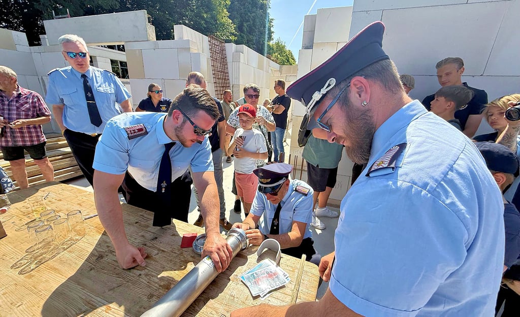 Die Zeitkapsel wird auf der Baustelle des Feuerwehrgerätehauses gefüllt und anschließend im Mauerwerk eingelassen.