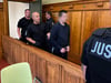 Der Angeklagte wird in Handschellen von mehreren Justizbeamten zur Urteilsverkündung gebracht.