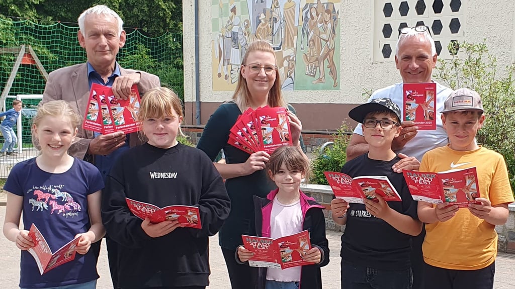 Ortsbürgermeister Jens Müller (BISS/SPD) sowie Stefanie Schrader und Schulleiter Volker Hein (hinten von links) überreichten die ersten Exemplare des Ferienkalenders an Chelsea, Anni, Isabel, Wolfgang und Max (vorn von links).