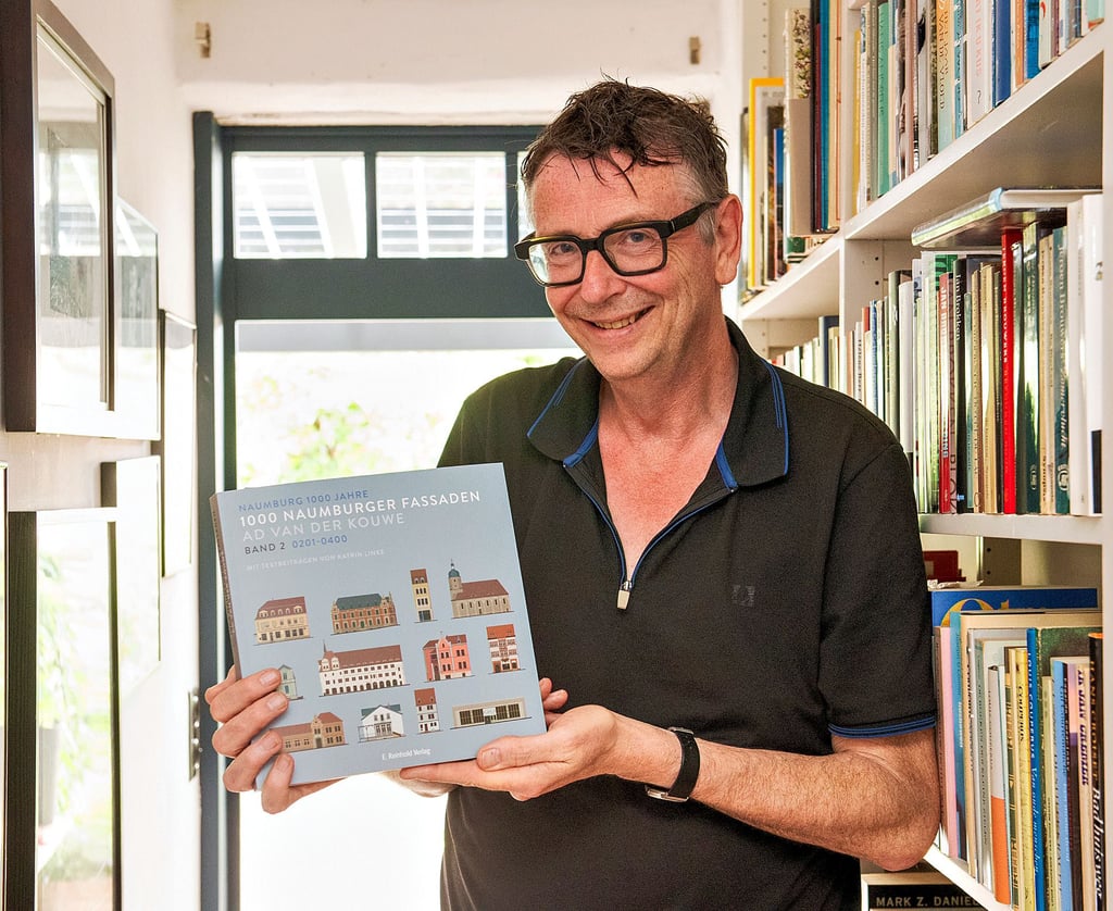 Der Grafikdesigner Ad van der Kowe in seinem Haus mit dem zweiten Band seines Projekts „1.000 Fassaden“ anlässlich des kommenden Stadtjubiläums. Am Freitag wird eine weitere Ausstellung in der Kunsthalle eröffnet.
