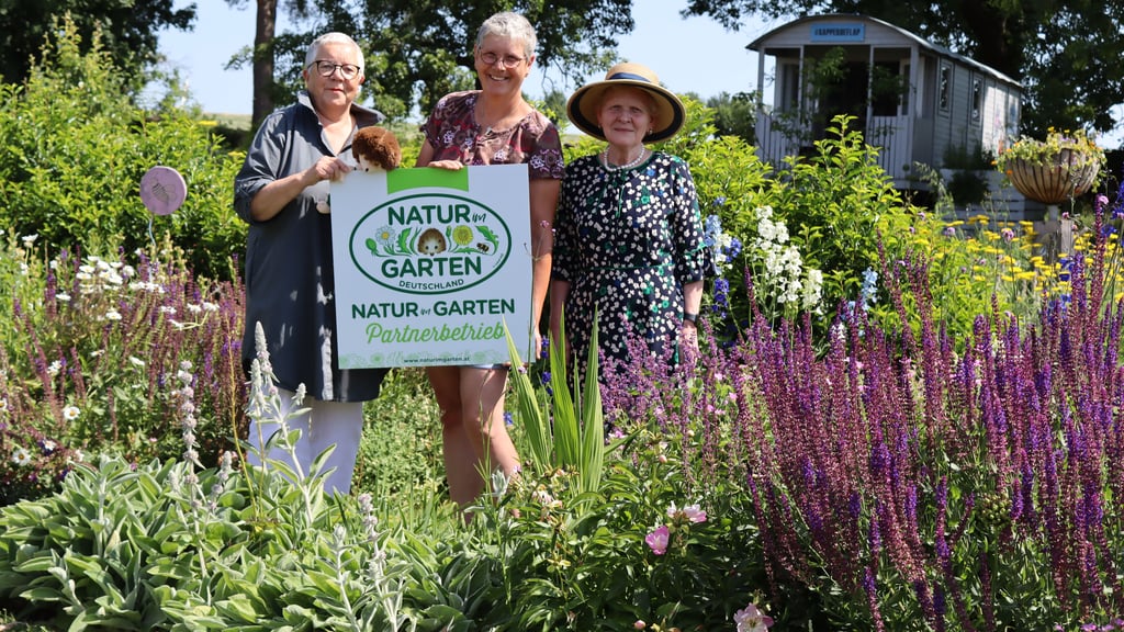 Christa Ringkamp (l.) und Steffi Trittel (r.) überreichen die Natur-im-Garten-Plakette als Partnerbetrieb an Jolanda van Amerom.