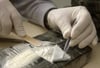 Ein Polizeibeamter kontrolliert ein Packet mit circa einem Kilo Kokain.