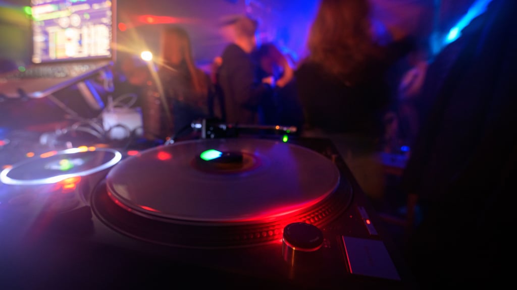 Partygänger tanzen vor einem DJ-Pult in einem Club. Nach zwei Techno-Partys im "Fuchsbau" in Blankenburg haben sich Anwohner wegen des Lärms beschwert. Die Veranstalter haben daraus die Konsequenzen gezogen.