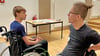 Für Thomas  Rösicke (rechts) gehört der Rollstuhl zum Alltag. Jason Balkau übt das Fahren damit und findet sich schnell sehr gut zurecht. 