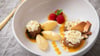 Dessert-Teller mit Schokoladen- und Mango-Mousse auf Mangopüree. Getoppt wird alles mit Eiswaffelsplittern, Schokoraspeln, Himbeeren und Minzblättern.