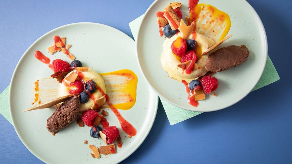 Sieht aus wie ein Bagel aus Eis: In sogenannte Savarin-Formen wird das Mangoeis gefüllt und gefroren. Die Mitte wird mit Fruchtigem gefüllt, dazu einen Klecks Schokoladenmousse, Mango- und Erdbeerpüree drunter und drüber streichen.