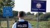 Ein Bundespolizist steht vor den Schildern für Deutschland und Polen. Als Reaktion auf die deutschen Kontrollen will nun auch Polen an der Grenze kontrollieren. (Archivbild)
