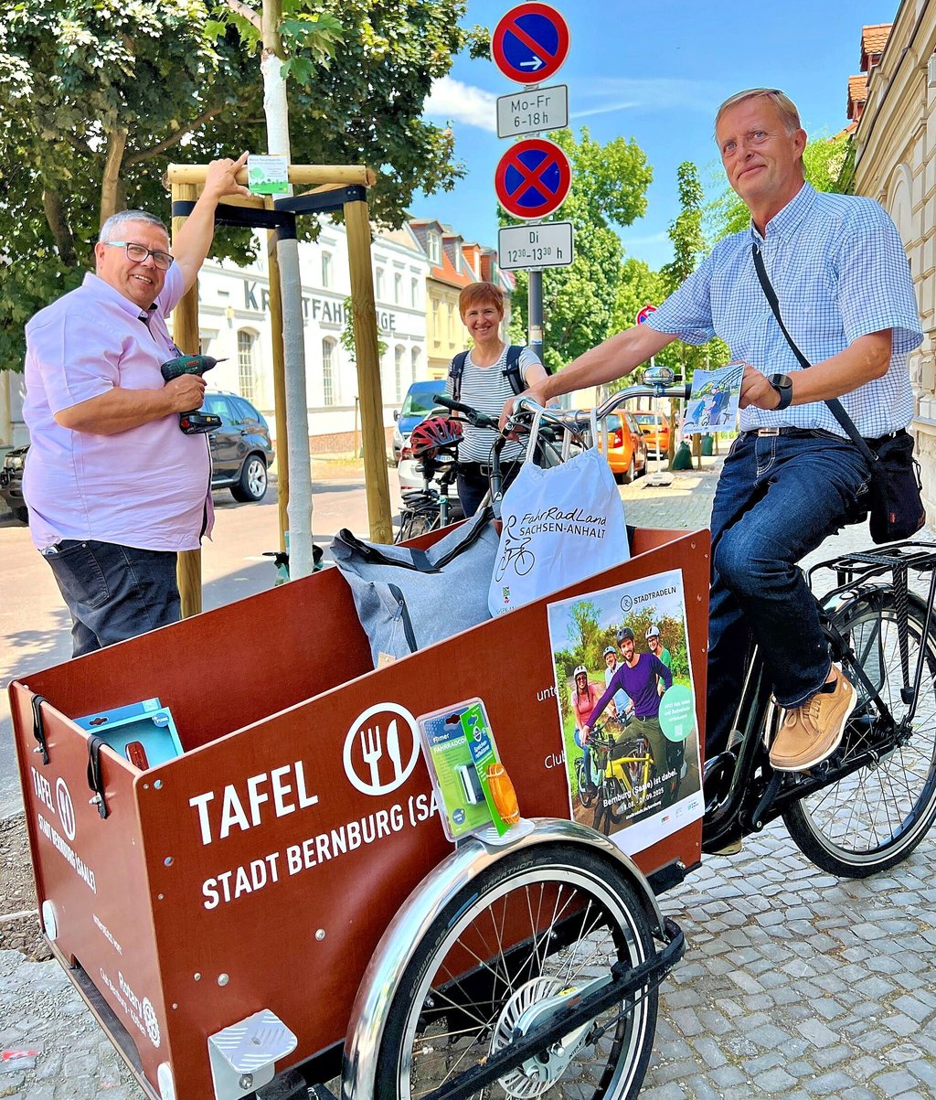Michael Angermann (links), Präsident des SC Bernburg, schraubte in der Vorwoche an der Hohen Straße im Beisein von Julia Tarlatt und Jens Meißner das Siegerschild vom Stadtradeln 2024 an den neu gepflanzten Baum.