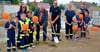 Symbolischer Spatenstich für das neue Haus der Ortsfeuerwehr Rathmannsdorf mit dem Staßfurter Bürgermeister René Zok (5. von links), Ortswehrleiter Benjamin Zuck und der Kinderfeuerwehr Lietheflämmchen (gegründet 2024) mit ihren Betreuerinnen vor der bereits ausgehobenen Baugrube.