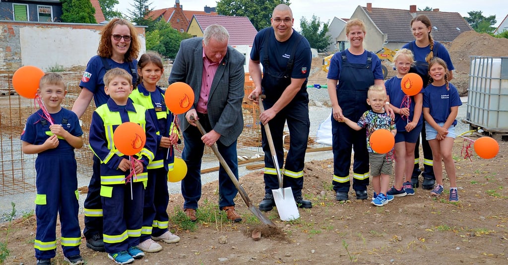 Symbolischer Spatenstich für das neue Haus der Ortsfeuerwehr Rathmannsdorf mit dem Staßfurter Bürgermeister René Zok (5. von links), Ortswehrleiter Benjamin Zuck und der Kinderfeuerwehr Lietheflämmchen (gegründet 2024) mit ihren Betreuerinnen vor der bereits ausgehobenen Baugrube.