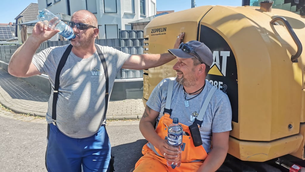 Hitze-Stopp auf der Baustelle: Die Tiefbauer Sandro John und Dennis Golacz nutzen den Schatten des Baggers, um kurz durchzuatmen. In der Gluthitze ssind die Werner-Bau-Mitarbeiter derzeit ind der Goslarer Straße in Magdeburg-Lemsdorf im Einsatz.