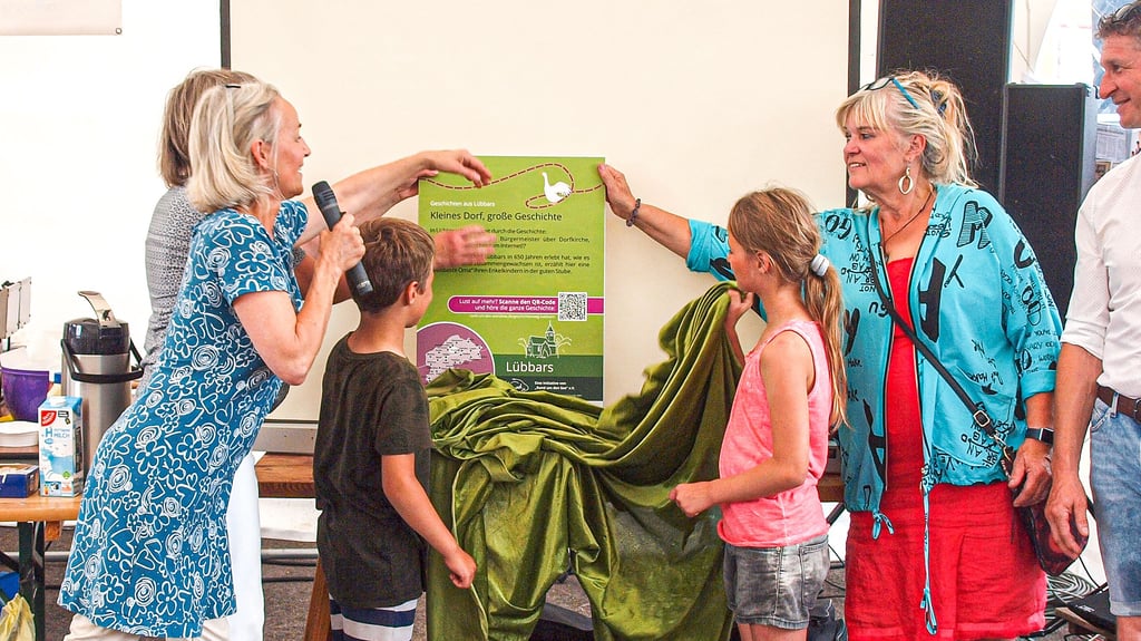 Birgit Muhl (verdeckt, von links), Kathrin Goyer und Petra Schrimpf enthüllten zusammen mit den Kindern Armin und Elina van Dam die neue Geschichtenweg-Tafel in Lübbars.
