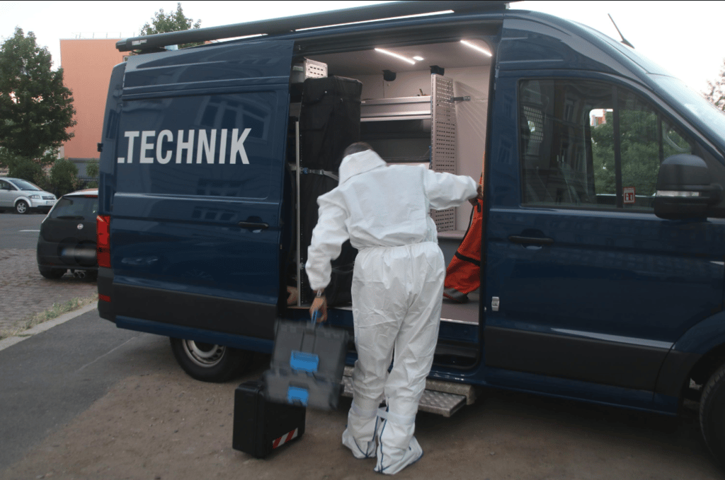 In Schutzanzügen betreten die Kriminaltechniker die Wohnung in Halle.