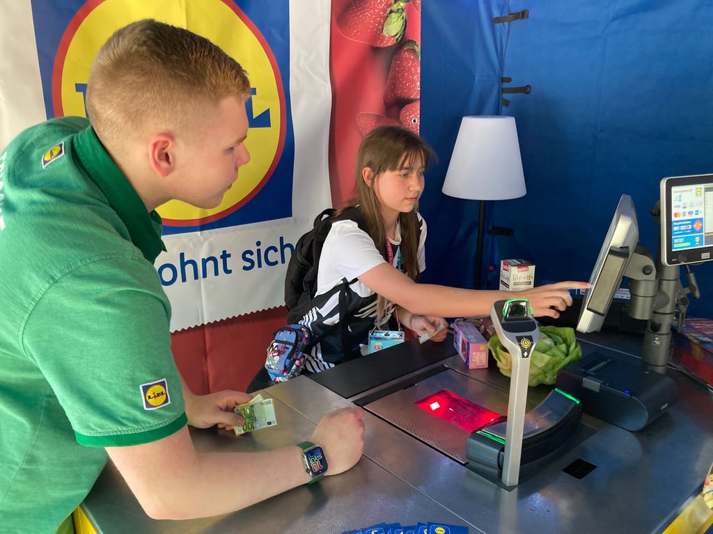 Pepe leitet Thea an der Lidl-Kasse an.