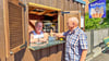Thomas Eckel (l.) reicht einem Kunden Softeis durchs Fenster seines umgebauten Holzunterstands in Pratau.