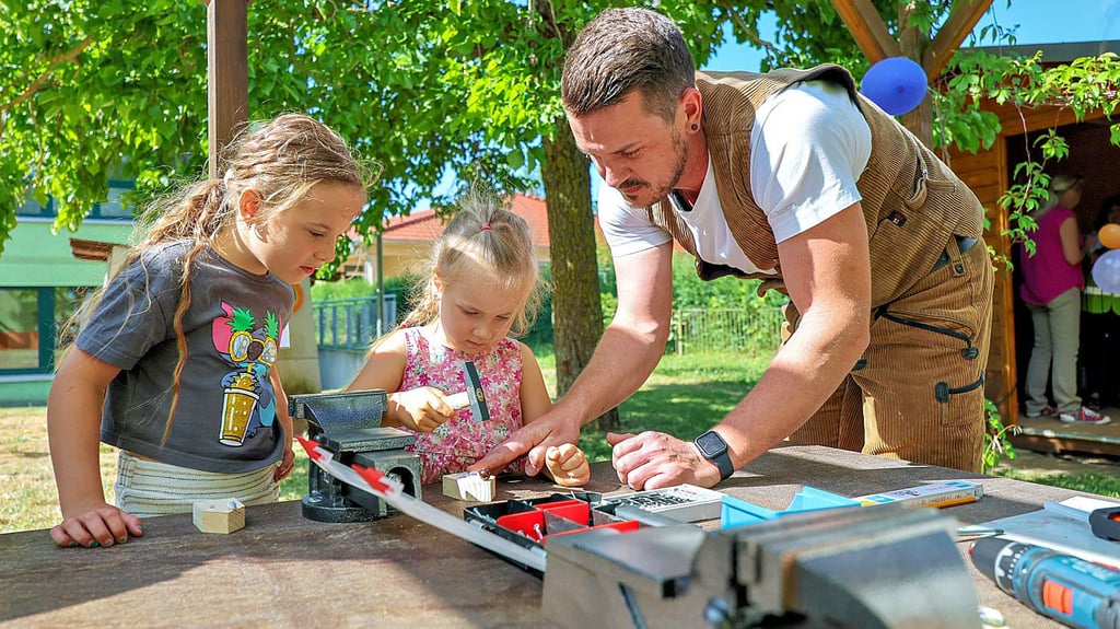 Lottiie Panzer (l.) und Marissa Stärz werkeln gemeinsam mit Tischlermeister Christoph Heller im Außenbereich der neuen Kinderwerkstatt.