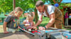 Lottiie Panzer (l.) und Marissa Stärz werkeln gemeinsam mit Tischlermeister Christoph Heller im Außenbereich der neuen Kinderwerkstatt.
