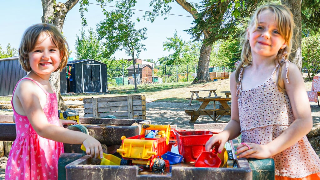 Isabell (l.) und Ella schätzen das Spiel im Schatten und die Erfrischung mit Wasser, bevor sie sich in die Gruppenräume zurückziehen.