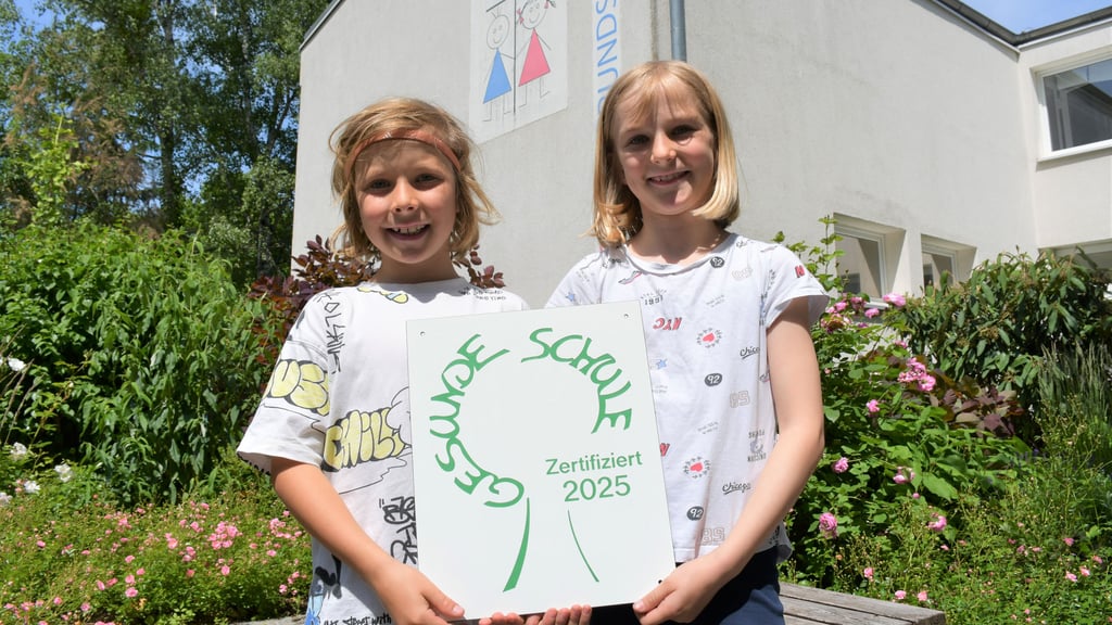 Anton und Charlotte zeigen das Siegel "Gesunde Schule", das die Evangelische Grundschule Magdeburg erstmals erhalten hat.