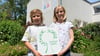 Anton und Charlotte zeigen das Siegel "Gesunde Schule", das die Evangelische Grundschule Magdeburg erstmals erhalten hat.