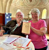 Gunter Böhnke erhält als Dank für seine zweite Benefizlesung in der Axiener Bücherkirche ein einzigartiges Buch mit Porträt überreicht. 