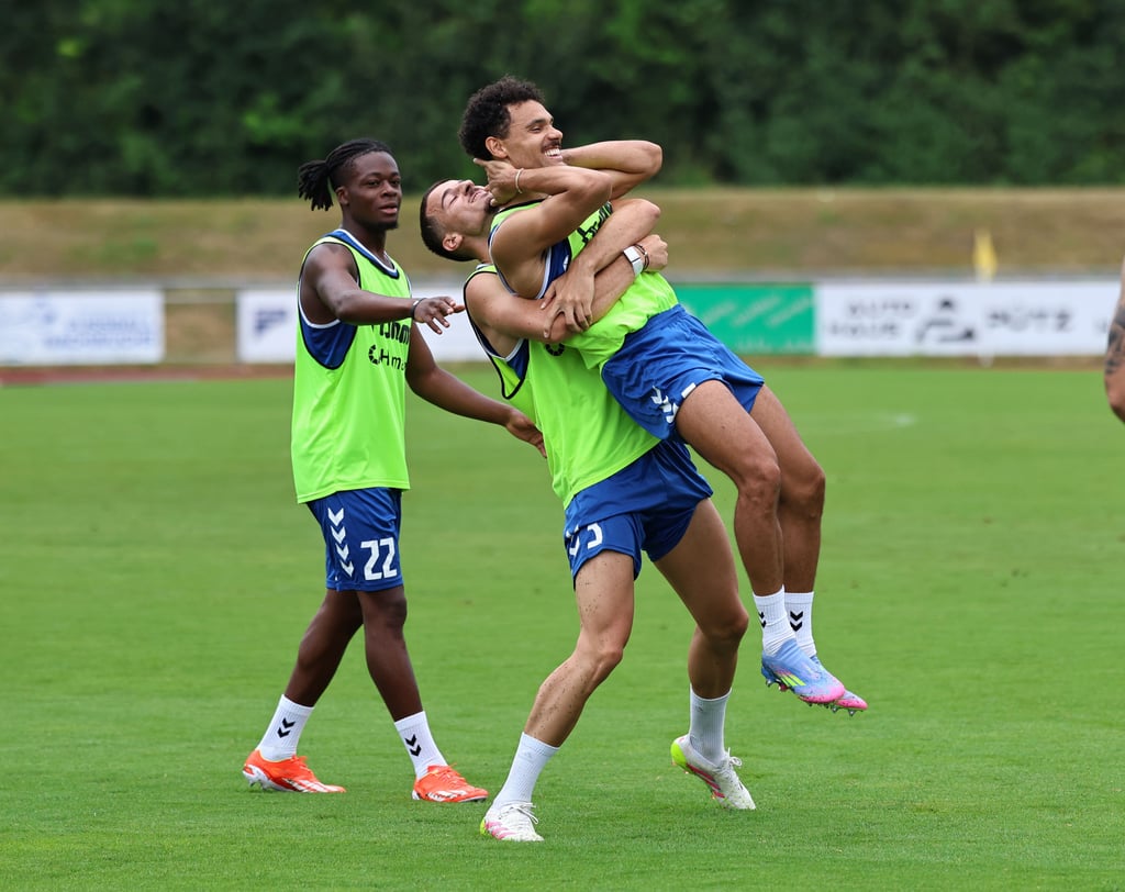 Toben macht Spaß: Andi Hoti hebt Herbert Bockhorn hoch, Pierre Nadjombe schaut belustigt zu.
