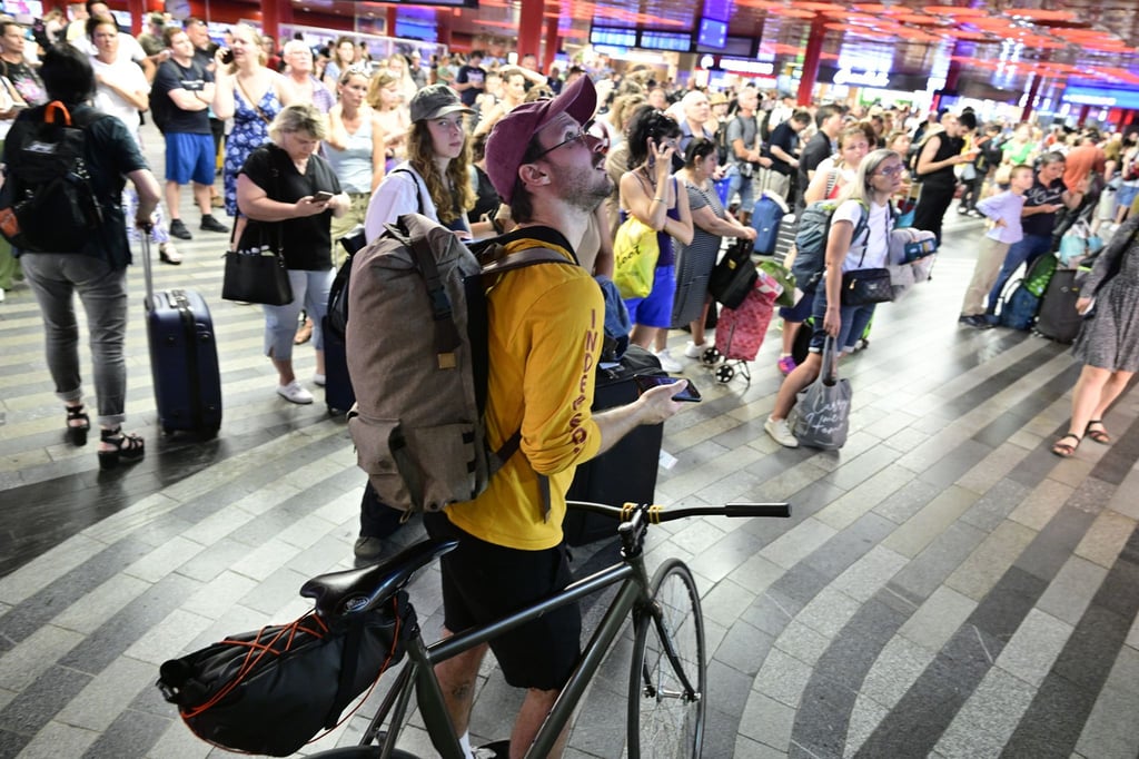 Passagiere sitzen in der Halle des Prager Hauptbahnhofs wähtrend eines Stromausfalls. Ein Stromausfall hat am Freitag große Teile Tschechiens und der Millionenmetropole Prag lahmgelegt.