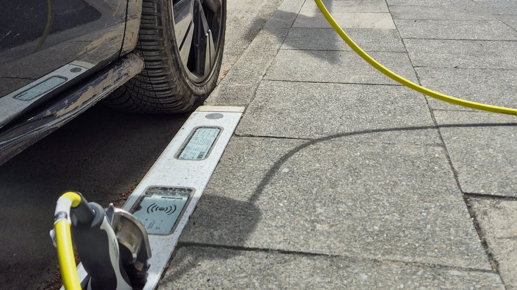 Ein E-Auto lädt an einem Ladebordstein. Die E-Ladebordsteine waren ein Pilotprojekt in Köln. In Magdeburg soll die Möglichkeit nun auch geprüft werden.