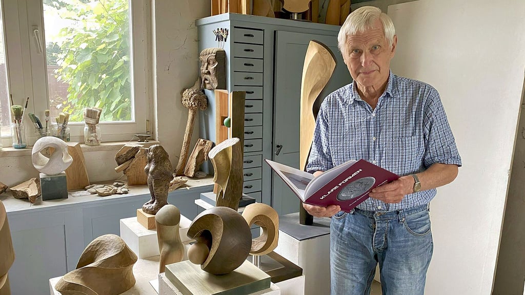 Klaus Kuhrmann neben einigen seiner Werke. In den Händen hält er sein neues Buch „Klare Formen“.