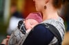 Ein Baby schlummert friedlich im Arm der Mutter. In Magdeburg warten Eltern bis zu zwölf Wochen auf die Geburtsurkunde.