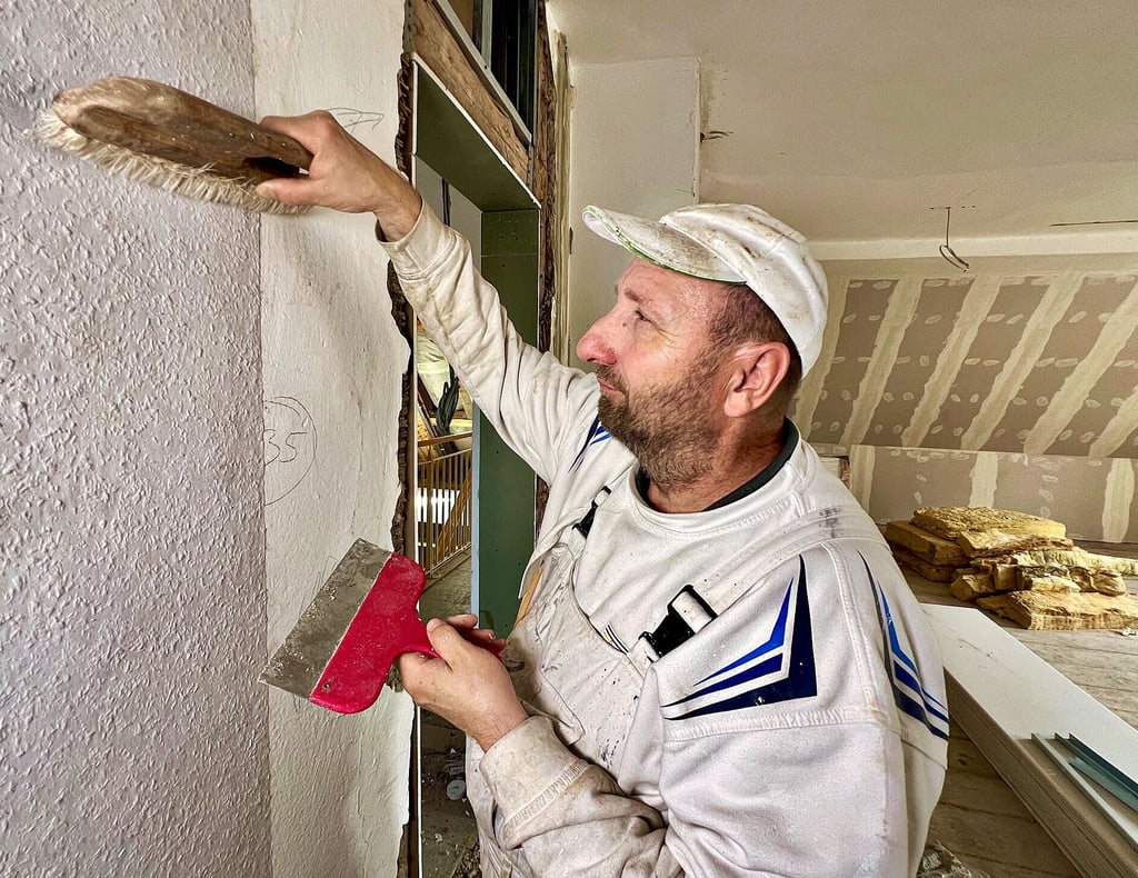 Andreas Bergmann tapeziert einen Raum im Dachgeschoss.