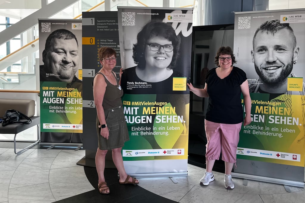 Gabriele Schmerbach (l.), Vertrauensfrau für die schwerbehinderten Mitarbeiter im Basedow-Klinikum, zeigt mit Mandy Bechmann den großen Aufsteller mit Mandys Porträt im Eingangsbereich der Querfurter Klinik.