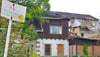 Auf dem verblichenen Schild ist die Aufschrift "Kureinrichtung Teufelsbad (Blankenburg)" zu lesen, rechts die Villa mit großen Schäden vor allem im Dachbereich.