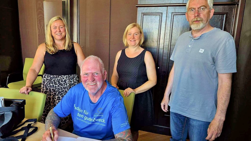 Bürgermeister Jörn Weinert (r.) und Mitstreiter der Initiative "Häkeln gegen Krebs" sind dabei, als sich Oliver Trelenberg (60) einträgt.
