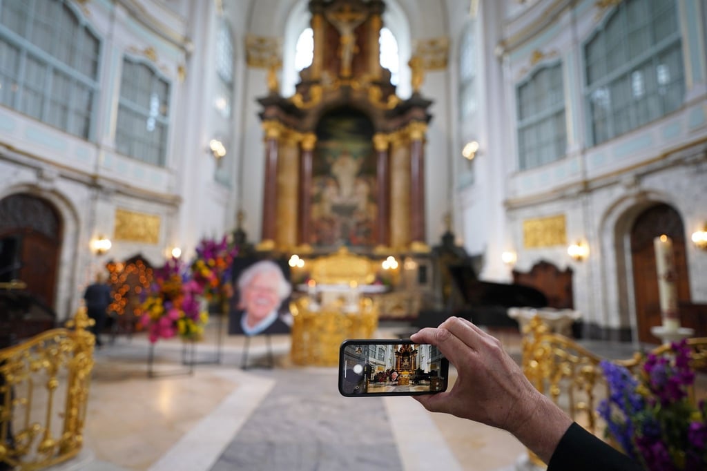 Ein Besucher macht zu Beginn der Trauerfeier ein Foto mit einem Smartphone.