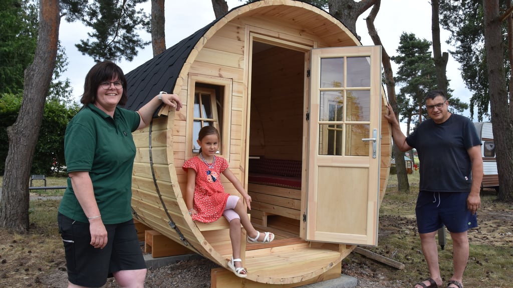 Nicole und Alexander Albrecht zeigen gemeinsam mit Nichte Sophie stolz das neue hölzerne Fass auf ihrem Naturcampingplatz in Wassensdorf. Es steht direkt an der Badekuhle.