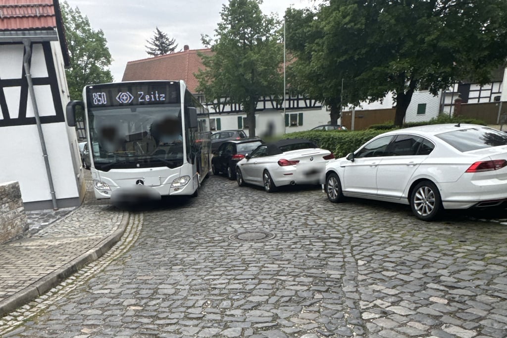 Ein Busfahrer zwängt sich in Predel mit seinem Fahrzeug an parkenden Autos vorbei.