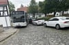 Ein Busfahrer zwängt sich in Predel mit seinem Fahrzeug an parkenden Autos vorbei. 