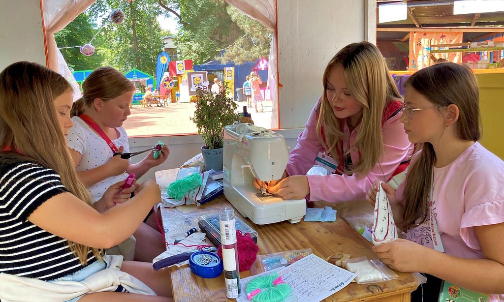 Die zehnjährigen Mädchen Johanna (von links), Anna und Ella (rechts) lernen bei der 16 Jahre alten Maja in der Kinderstadt-Schneiderei den Umgang mit einer Nähmaschine. Unter anderem wurden die Requisiten für das Theaterstück „3 kleine Schweinchen in Bärenhausen“ selbst geschneidert.