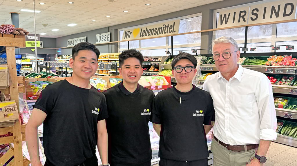 Edeka-Marktleiter Gunther Weiß mit drei vietnamesischen Auszubildenden.