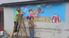 Harzmalerin Angela Peters und Erika von der Höhlenforschergruppe Rübeland erneuerten das Wandbild am Vereinssitz in Rübeland.