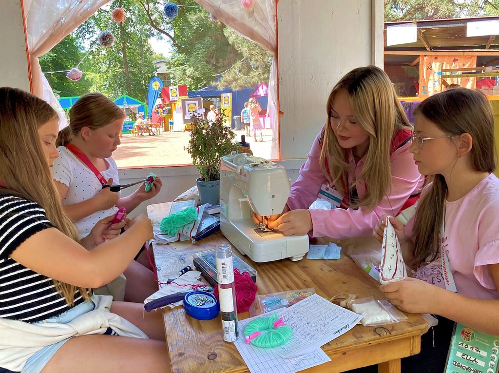 Die zehnjährigen Mädchen Johanna (von links), Anna und Ella (rechts) lernen bei der 16 Jahre alten Maja in der Kinderstadt-Schneiderei den Umgang mit einer Nähmaschine. Unter anderem wurden die Requisiten für das Theaterstück „3 kleine Schweinchen in Bärenhausen“ selbst geschneidert.