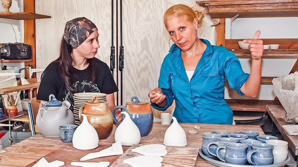 Anna Zorra Bölke (rechts) in ihrer Schramper Atelier-Werkstatt mit Goldschmiedin Nora Sbach. Sie präsentiert fertig gedrehte und lackierte Kannen sowie einige Rohlinge, die noch trocknen müssen.