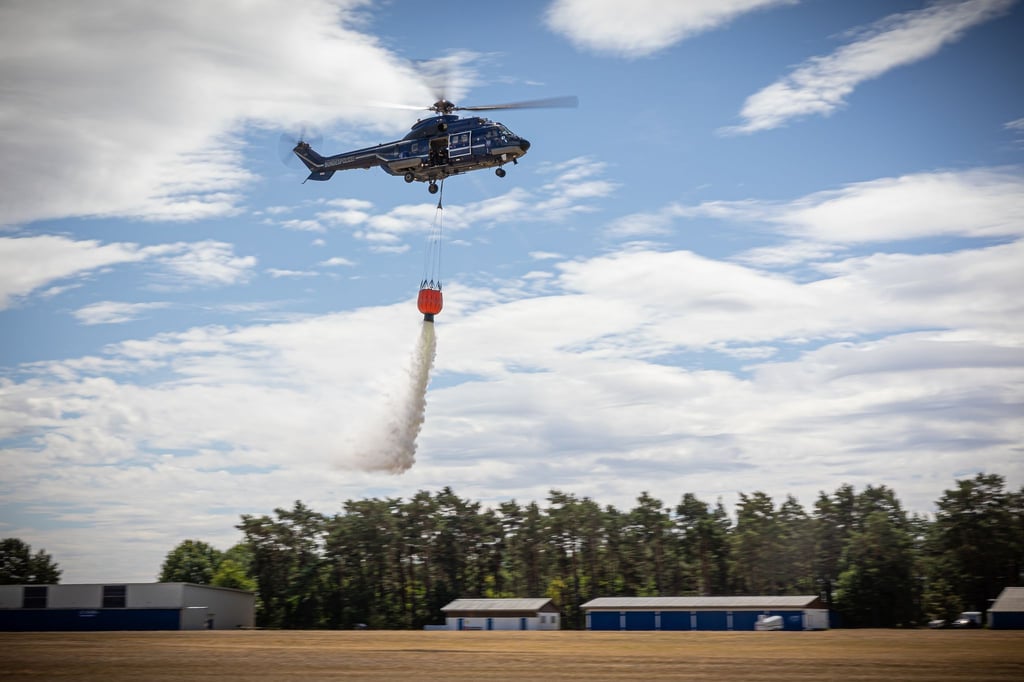 Ein Hubschrauber der Bundespolizei wirft bei einer Waldbrandübung Wasser aus einem Löschwasserbehälter ab.