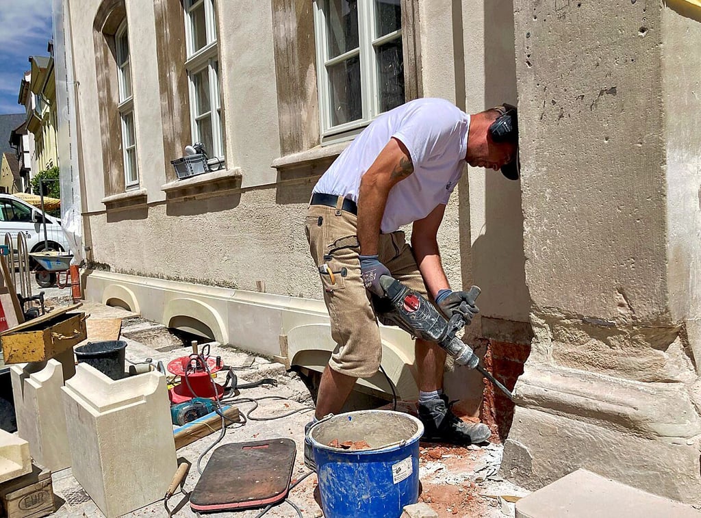 Guido Hecker von den Werkstätten für Denkmalpflege in Westerhausen arbeitet am Sockel des restaurierten Denkmals Markt 28.